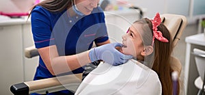 Dentist examining his girl patient in dentistÃ¢â¬â¢s photo